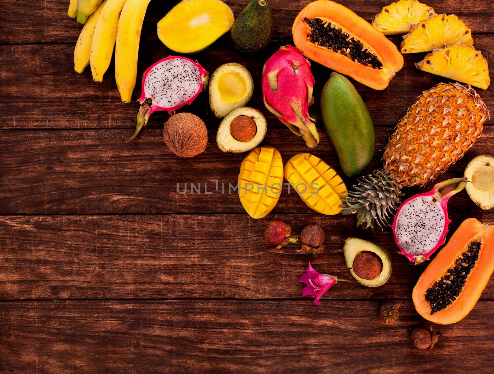 Tropical fruit on dark wooden background, top view by Jyliana