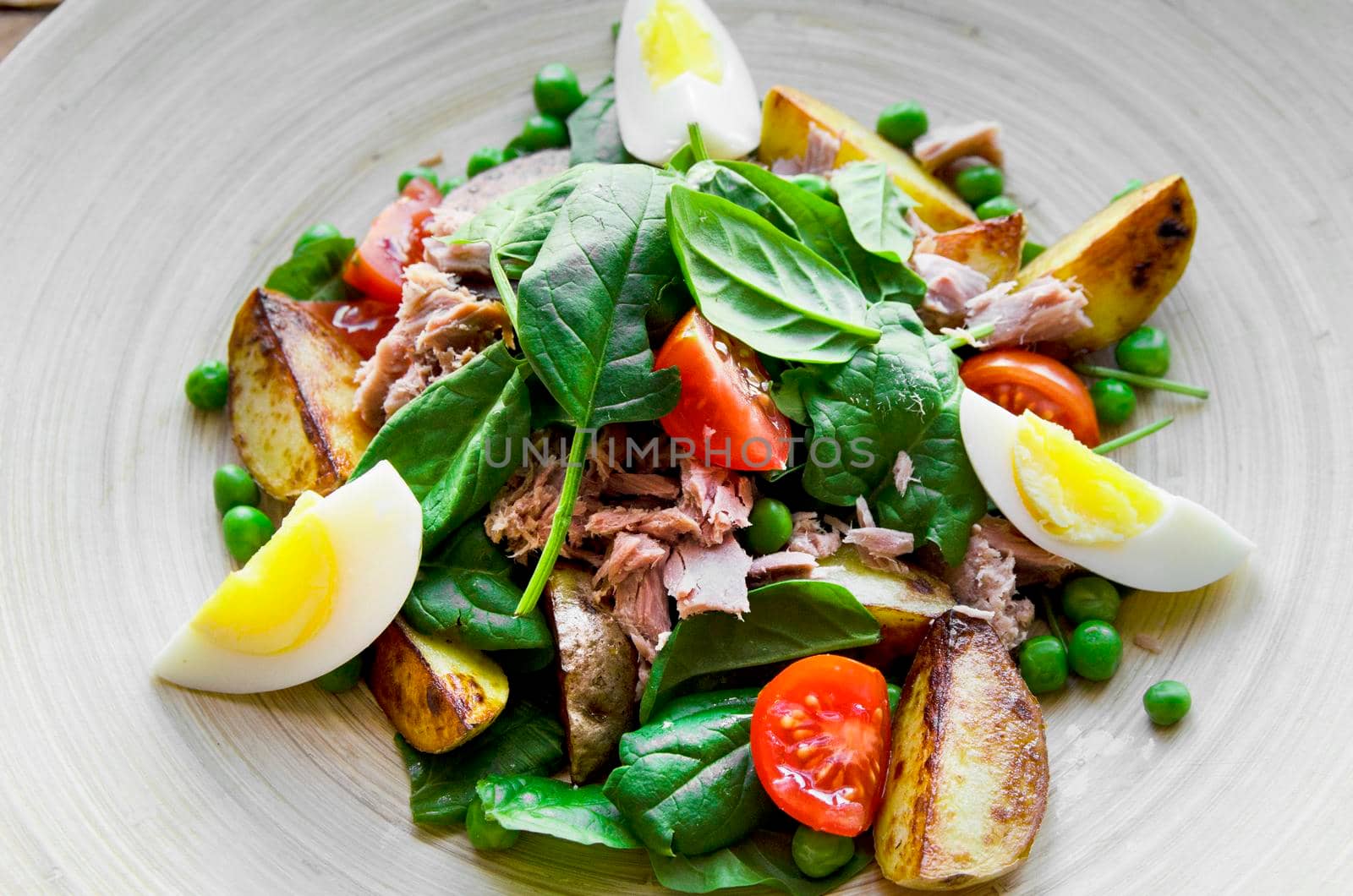 Tuna salad with lettuce, eggs and tomatoes on wooden plate