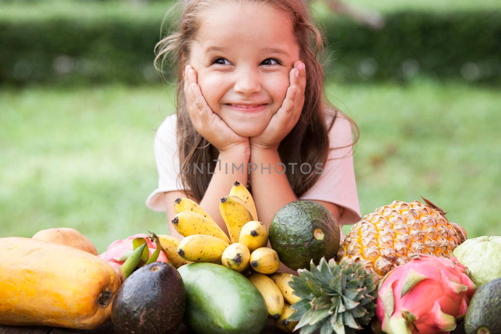 Exotic fruit on wooden table. Summer background with Laughing happy girl by Jyliana