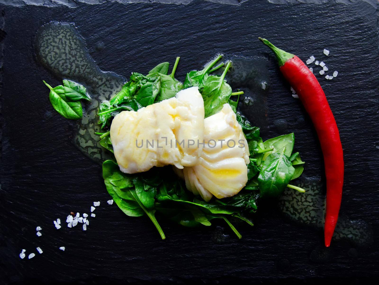 Delicious sea fish fillet with fresh healthy spinach and chili - Stock image