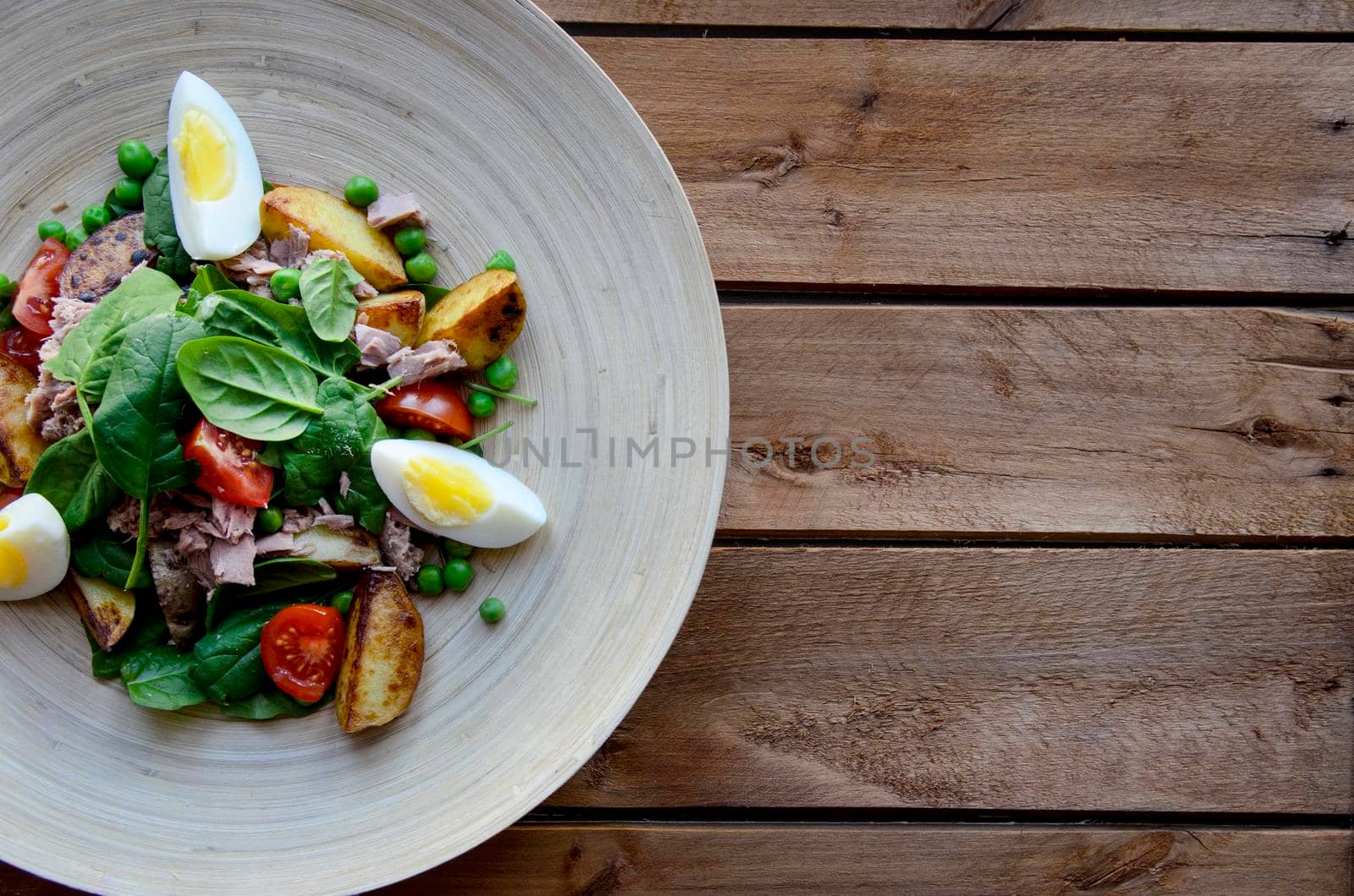 Tuna salad with lettuce, eggs and tomatoes on wooden plate