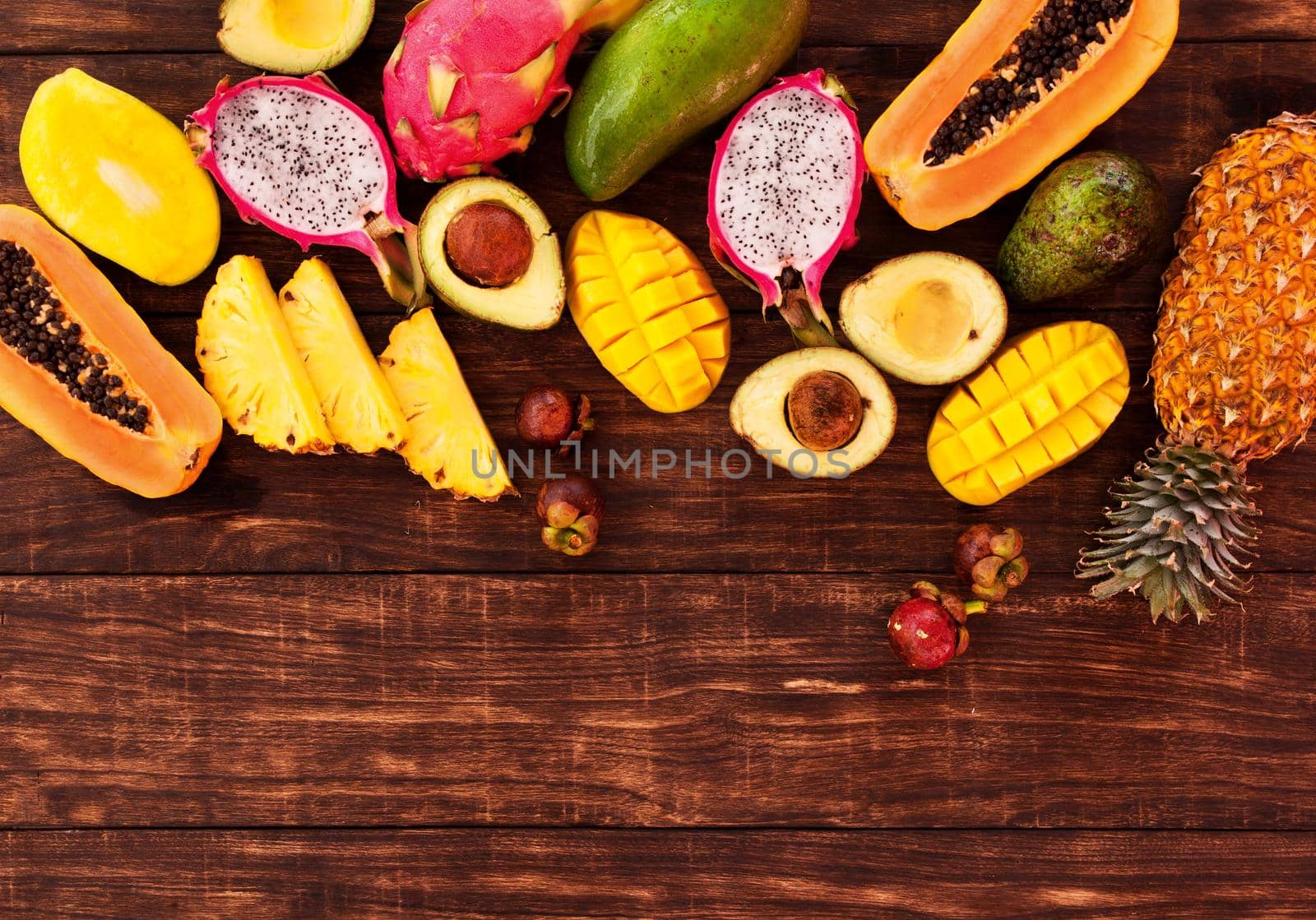 Tropical fruit on dark wooden background, top view by Jyliana