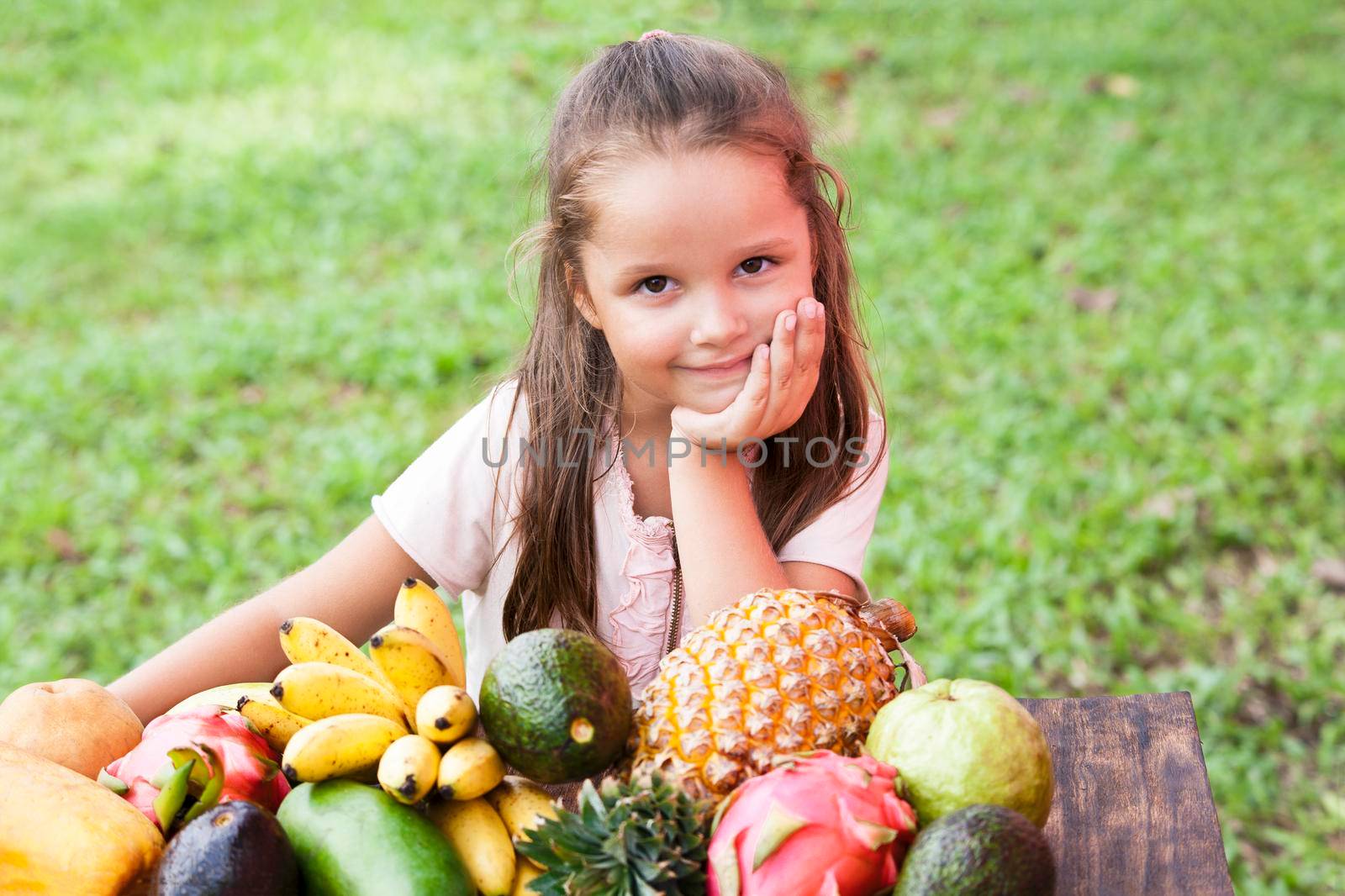 Exotic fruit on wooden table. Summer background with Laughing happy girl by Jyliana