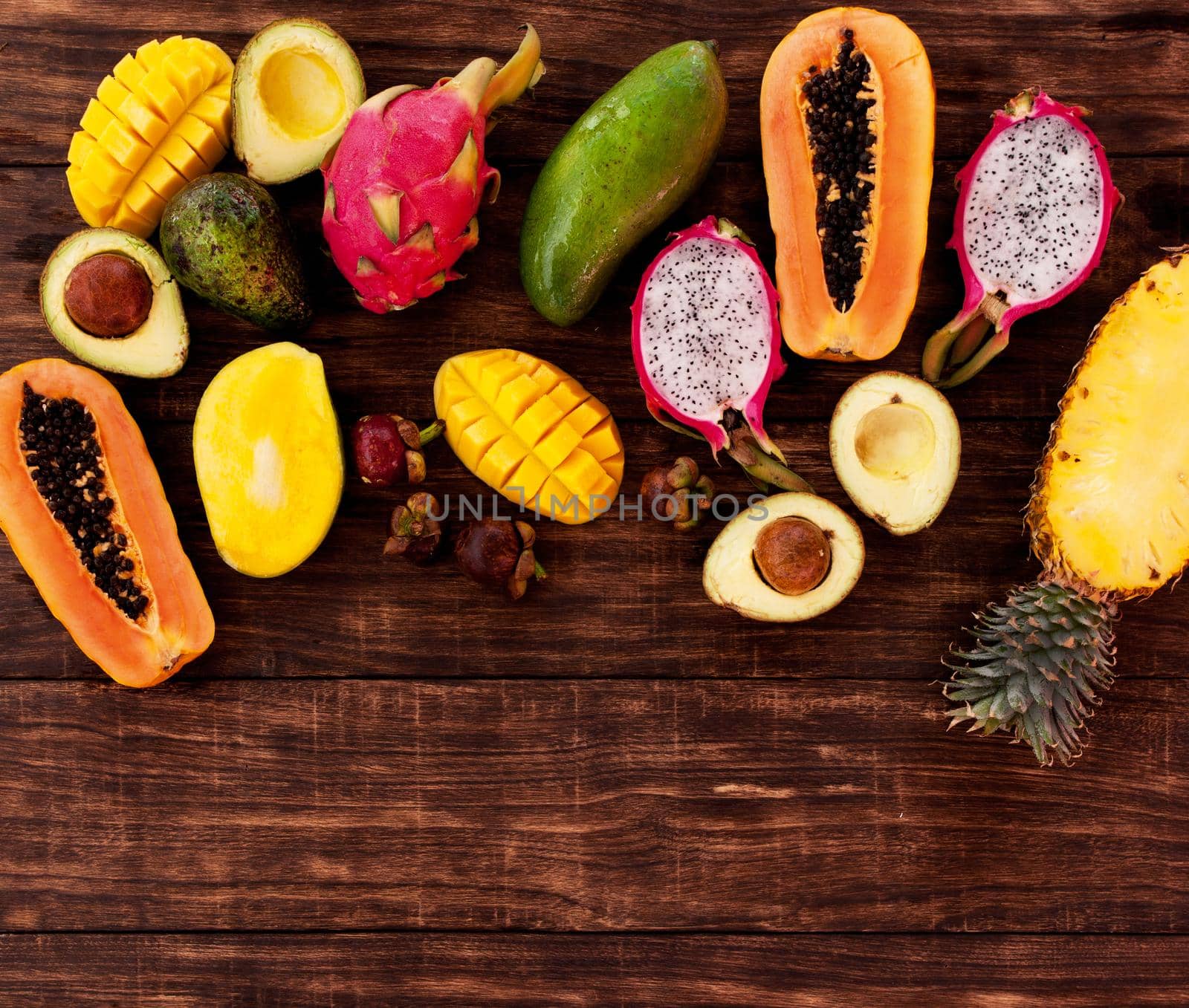 Tropical fruit on dark wooden background, top view by Jyliana