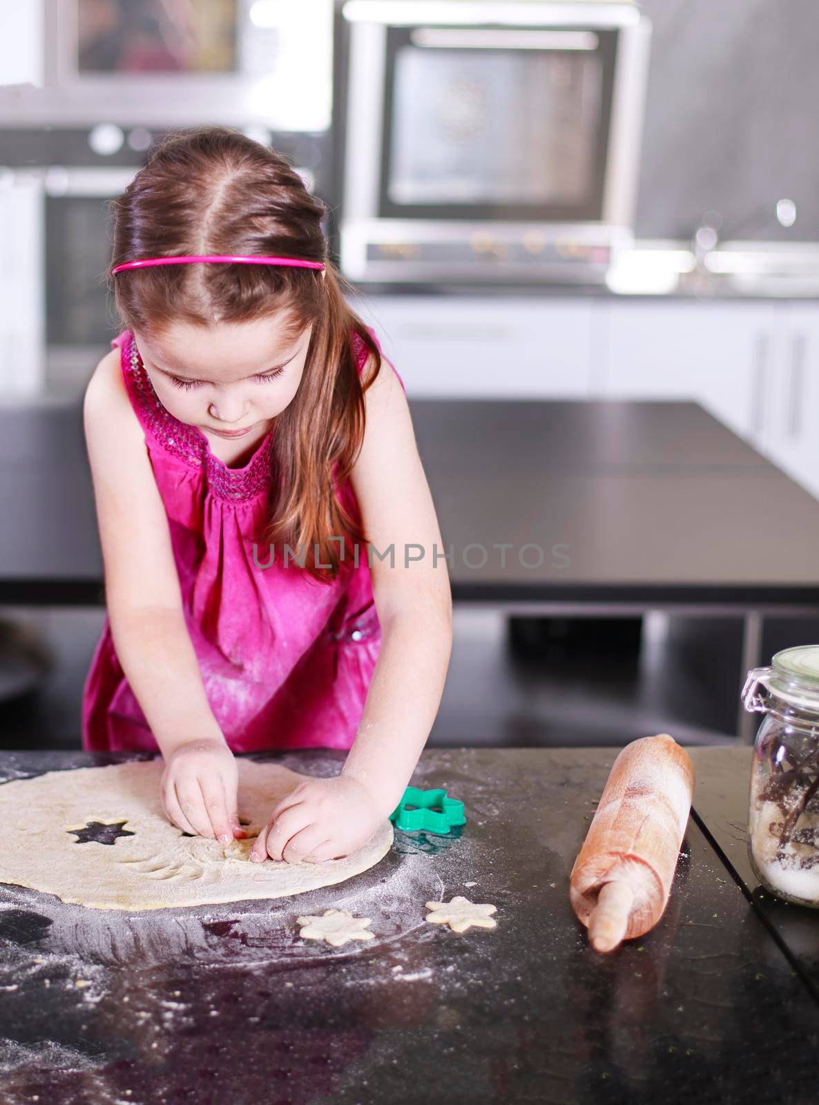 Sweet little cute girl is learning how to make a cake, in the home modern kitchen, Family concept