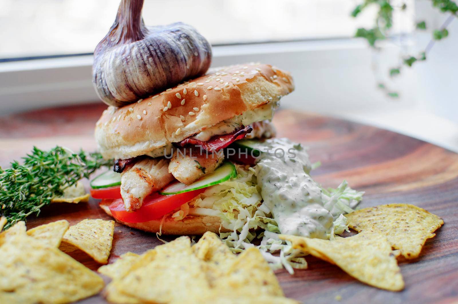 Creatively styled beef burger with rustic home-made French chips or crisps shot against light white background with generous accommodation for copy space. garlic on top