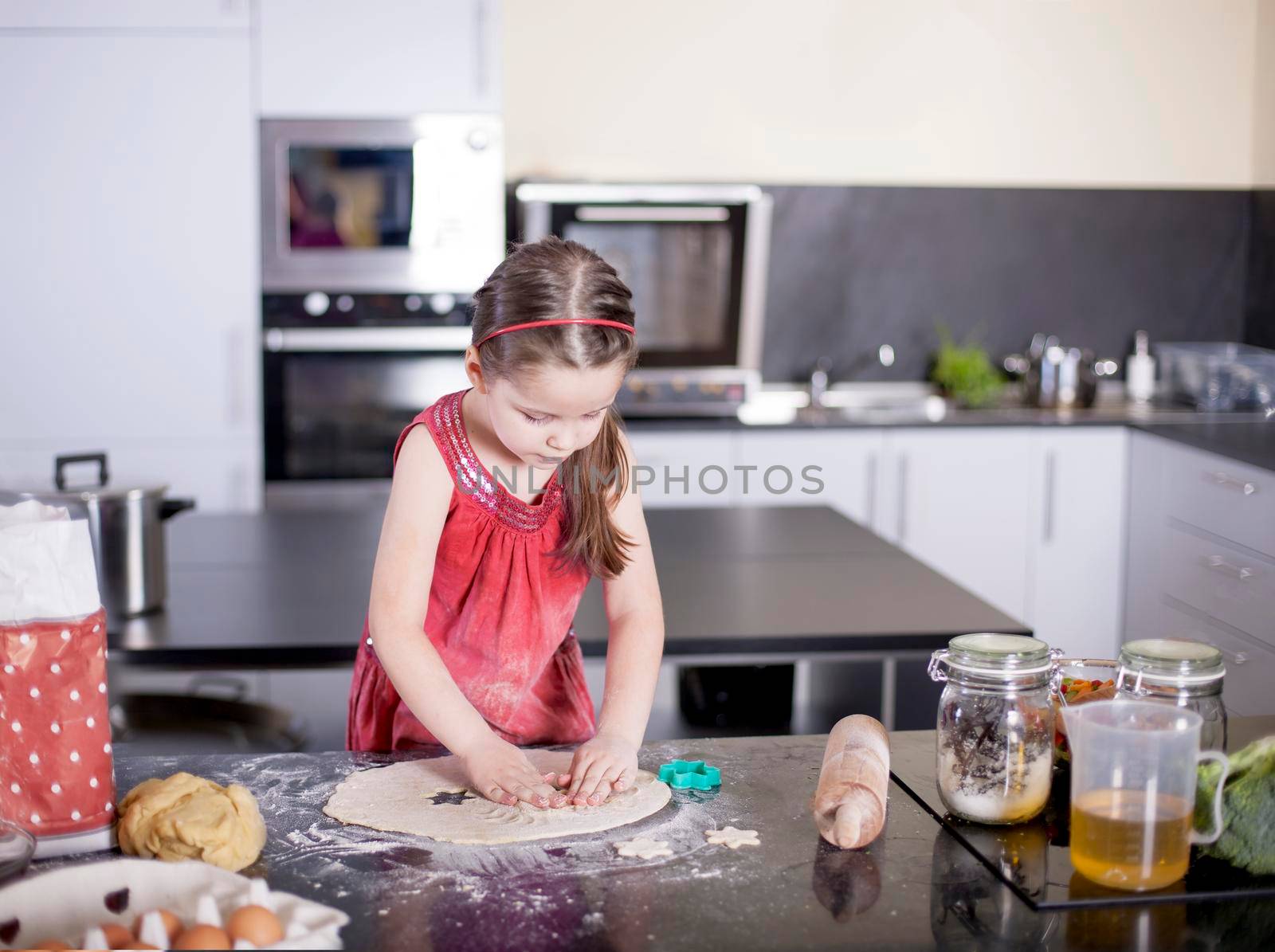 Sweet little cute girl is learning how to make a cake, in the home modern kitchen, Family concept