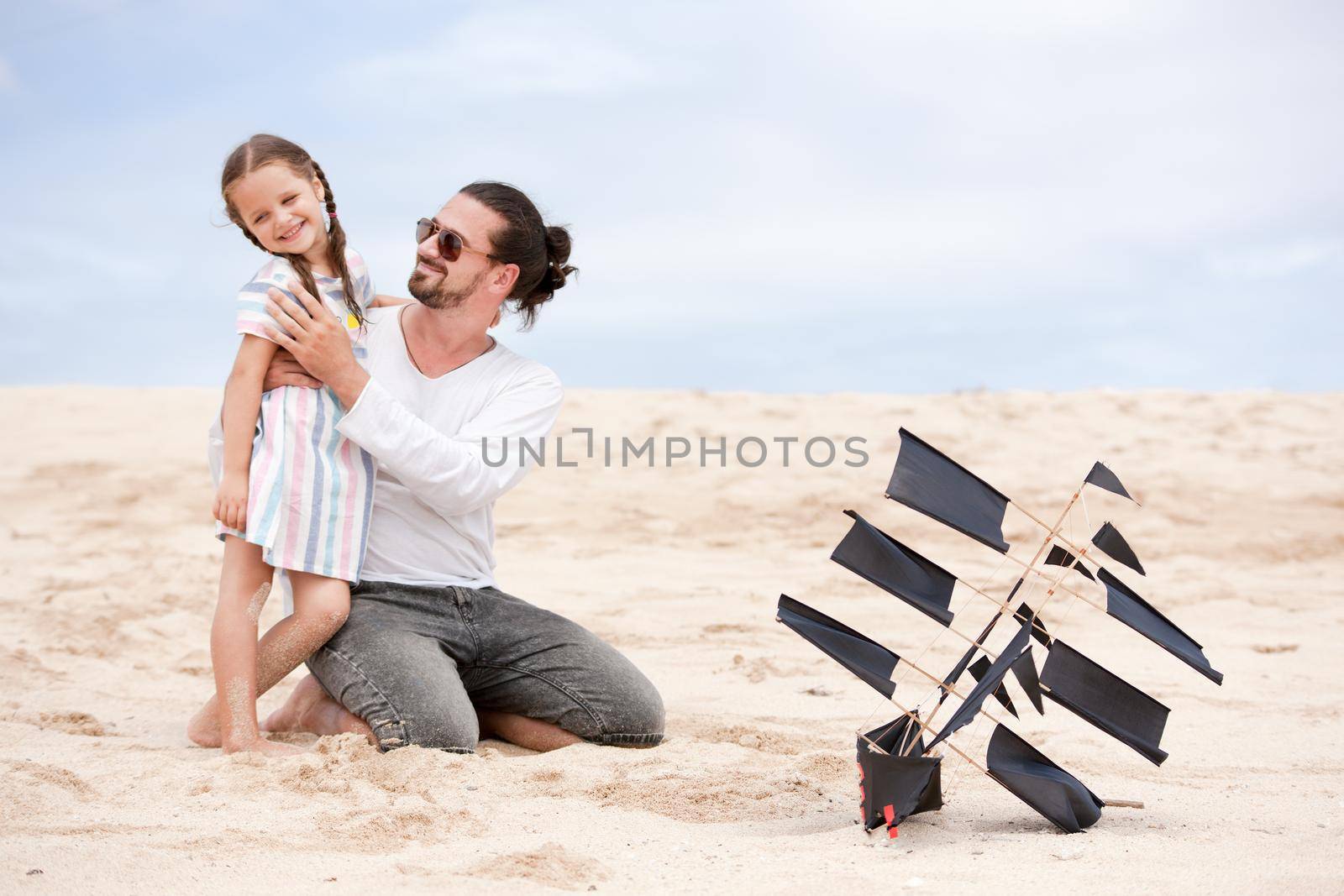 Beach cute girl with her happy father flying kite outdoor coast ocean