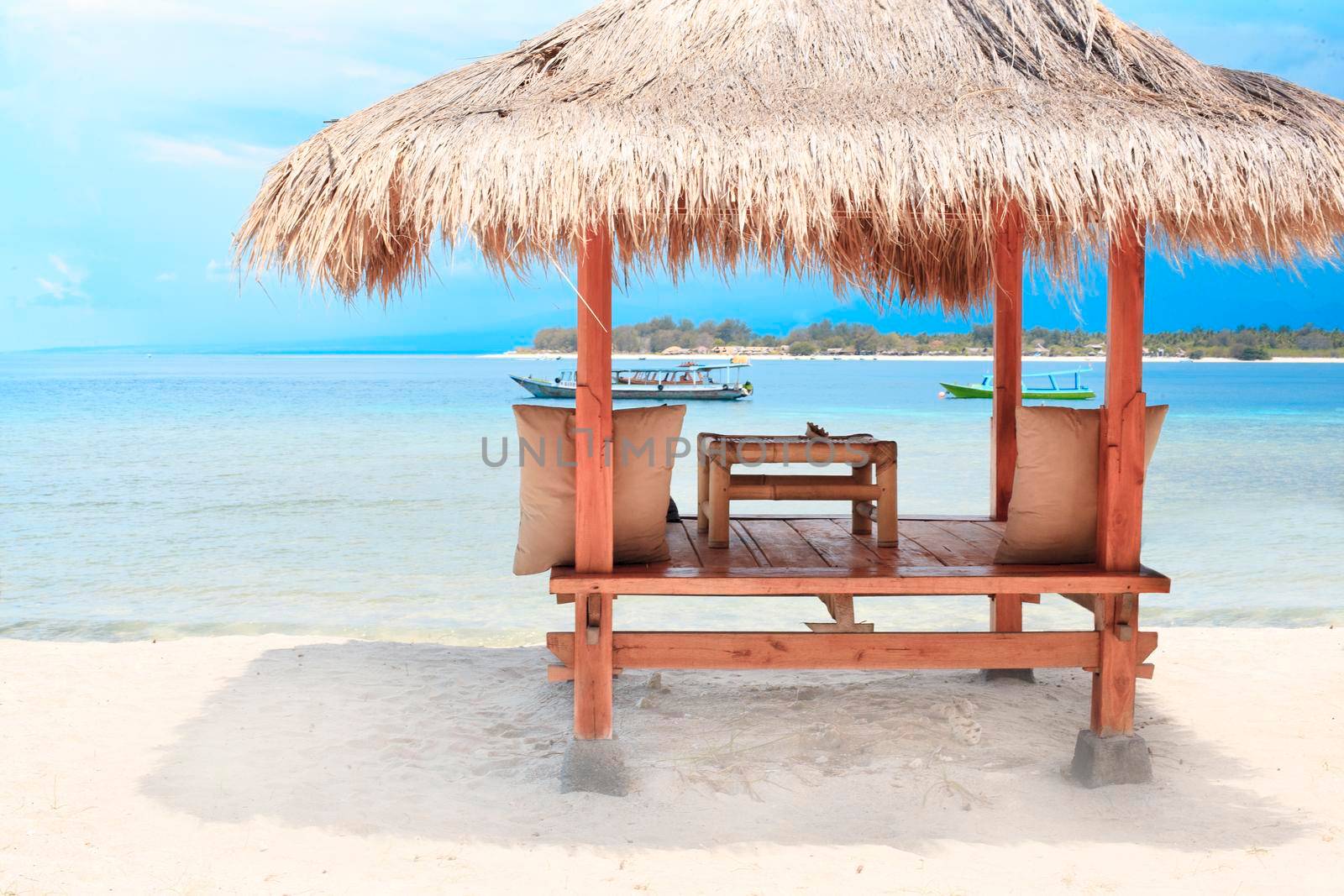 White wooden shelter with straw roof from the sun on the beach in Bali or Thailand. Gili island