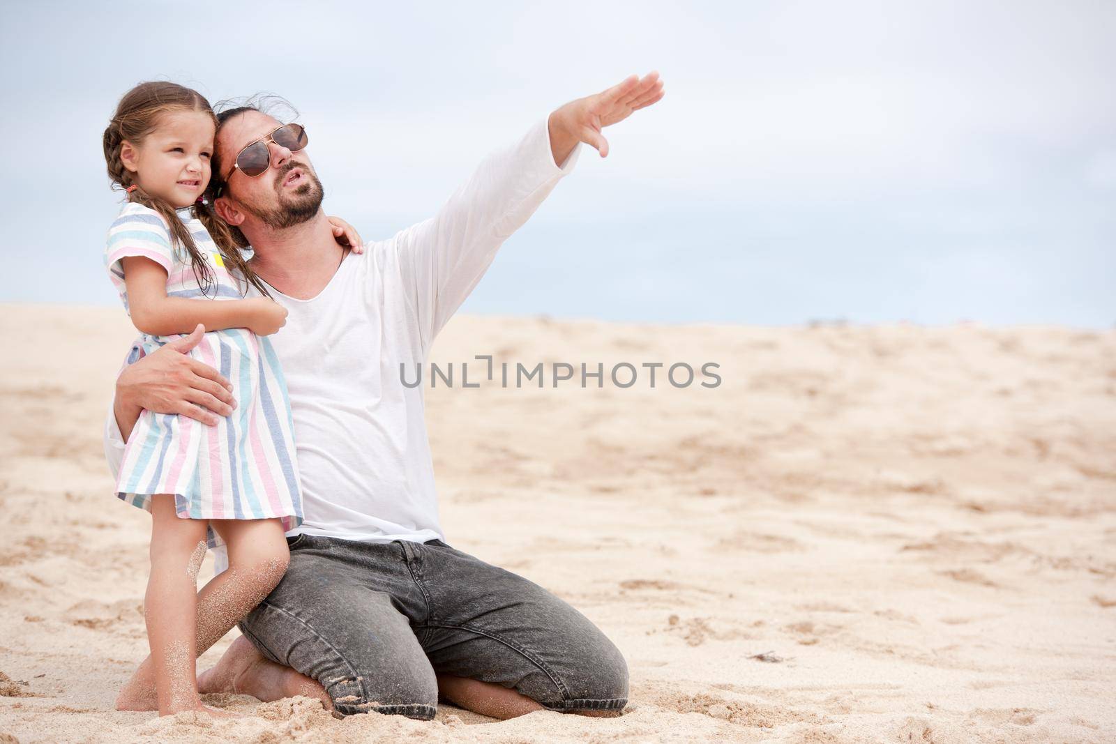 Beach cute girl with her happy father outdoor coast ocean. Father points to something