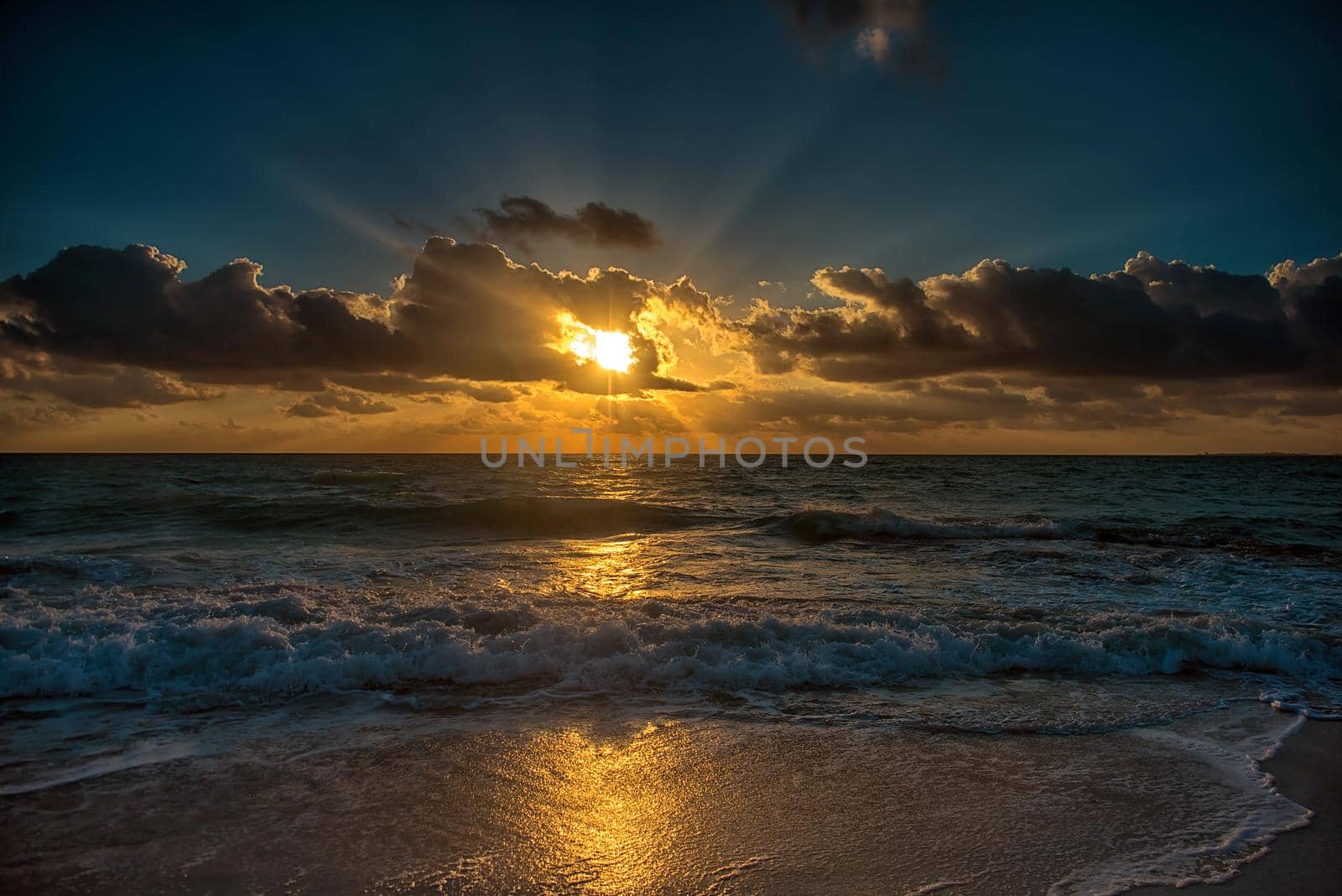 Sunset on the Caribbean Sea. The sun's rays make their way through the clouds.