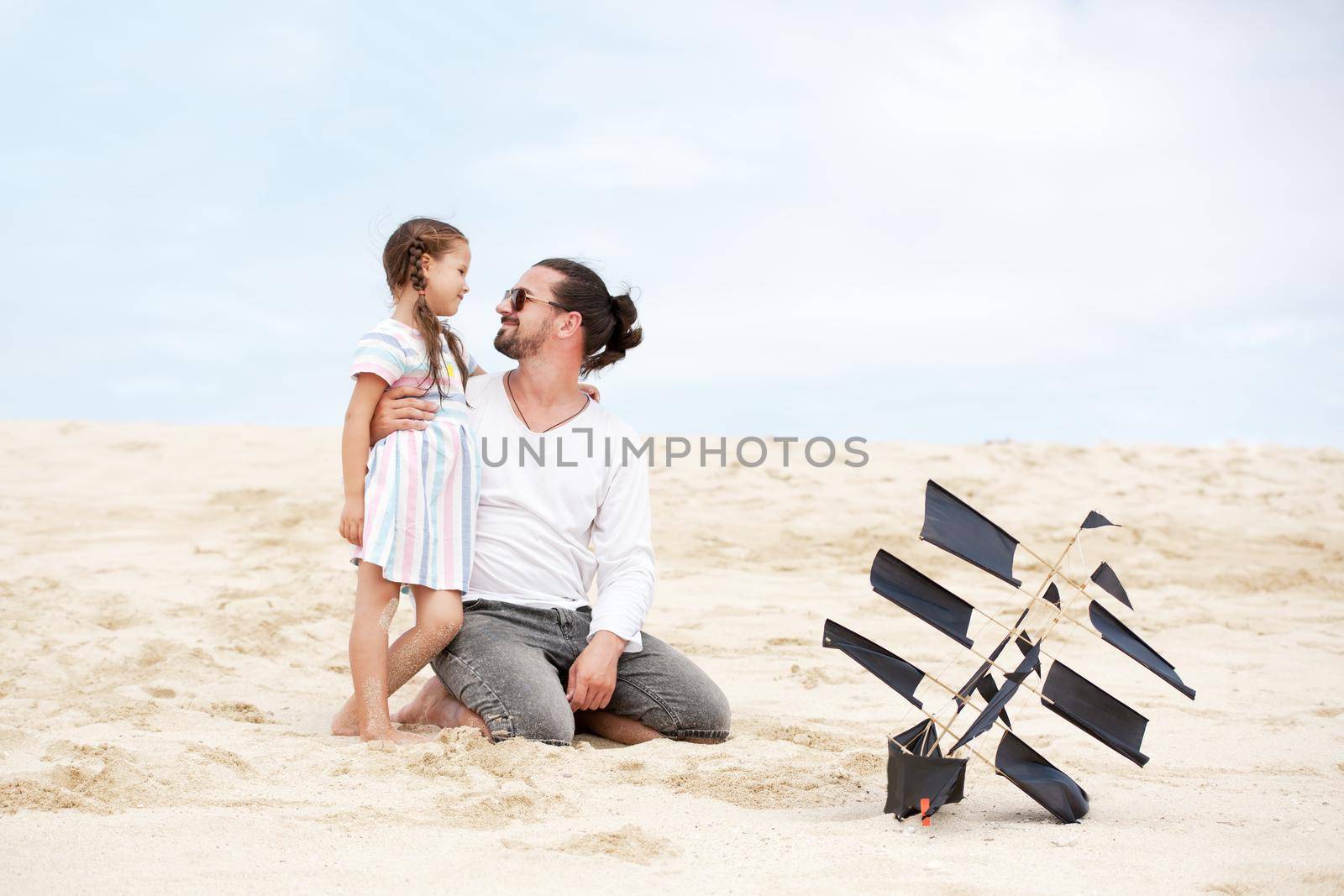 Girl with her happy father flying kite coast ocean by Jyliana