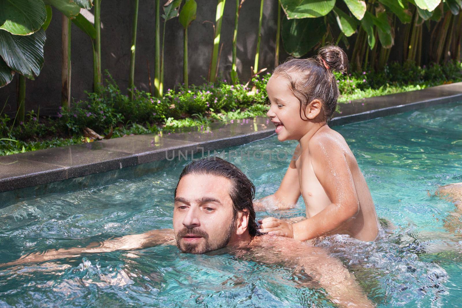 Happy family, active father with little child, adorable toddler daughter, having fun in swimming pool. by Jyliana