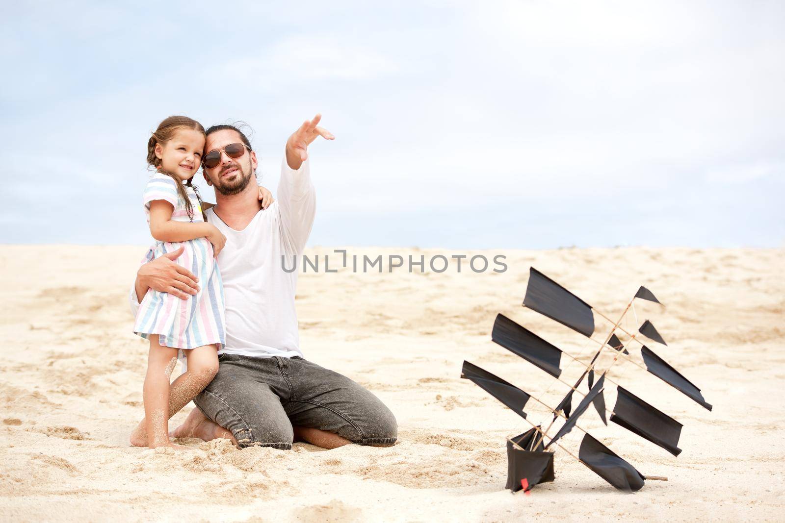 Girl with her happy father flying kite coast ocean by Jyliana