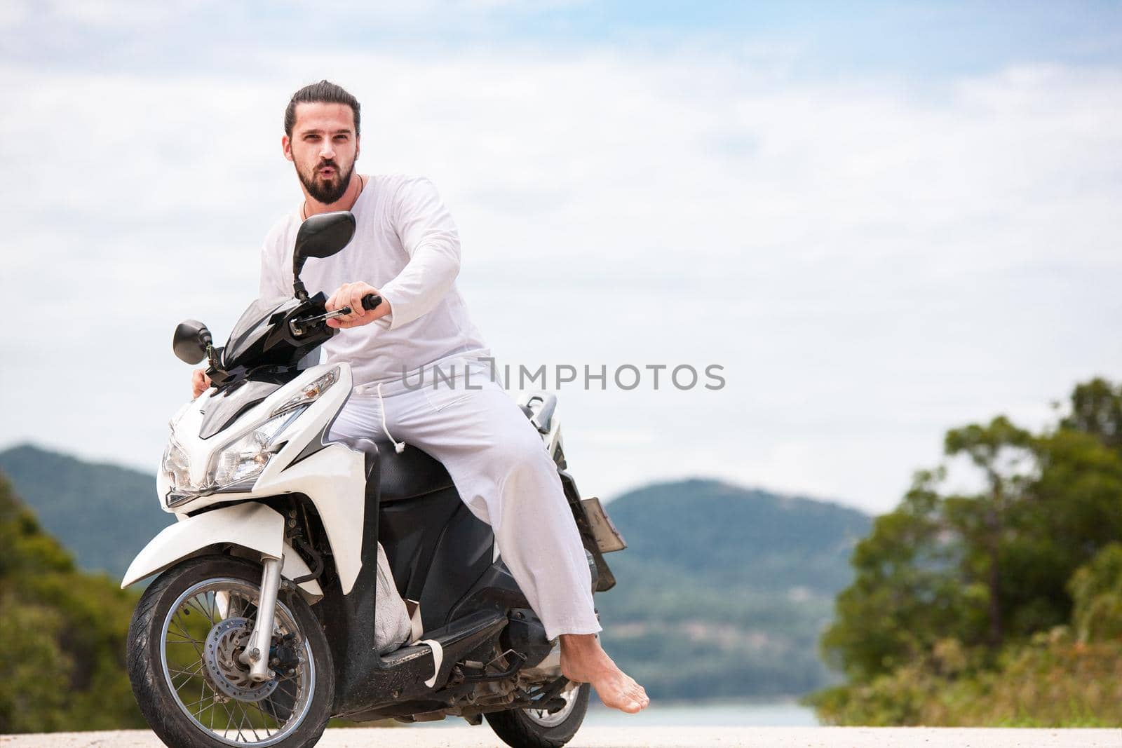 Brutal biker with beard sitting on motorbike in mountains. by Jyliana