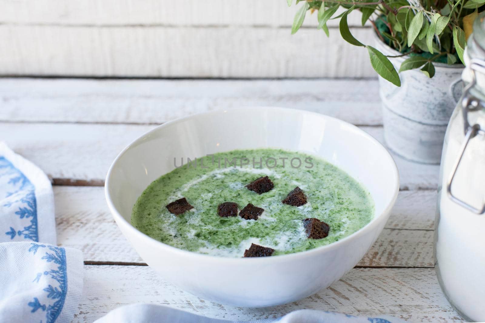 Spinach soup with croutons in red bowl on wooden table