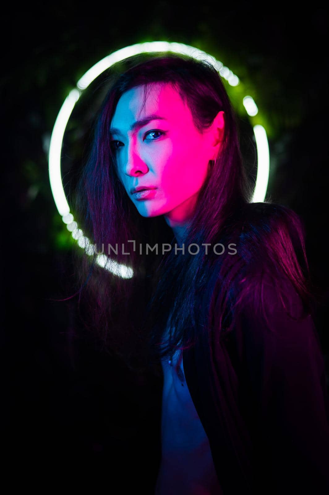 Portrait of an Asian man against the background of a circular lamp in the studio with neon light. by mrwed54