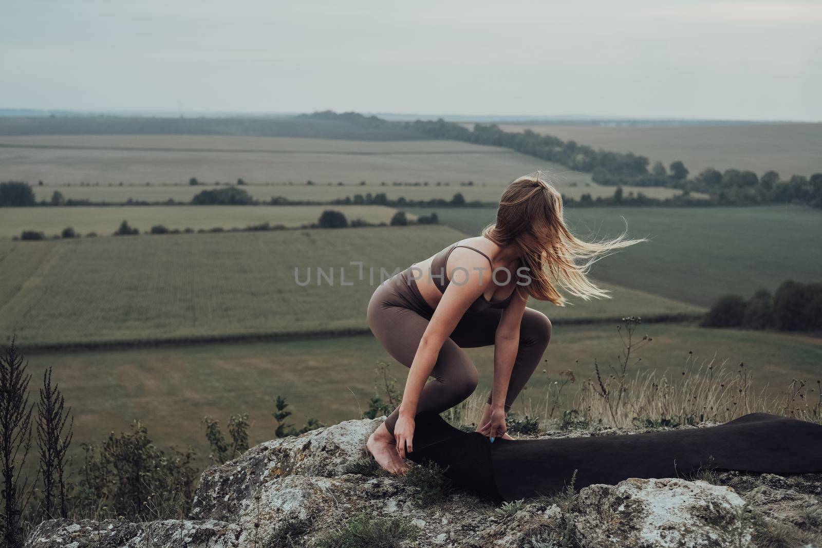 Young Woman Preparing Place for Workout Outdoors, Girl with Karemat on Top of Hill