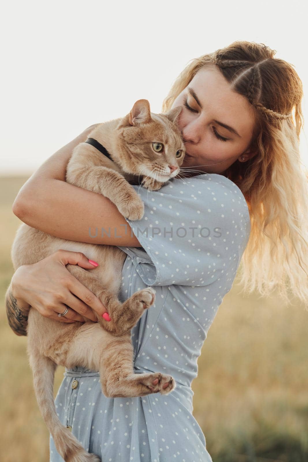 Caucasian Young Woman Dressed in Blue Dress Holding Her Cat Outdoors at Sunset