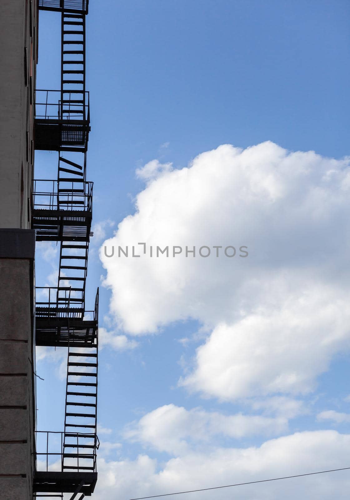 Silhouette of a fire escape on a high-rise building against a blue sky by AnatoliiFoto