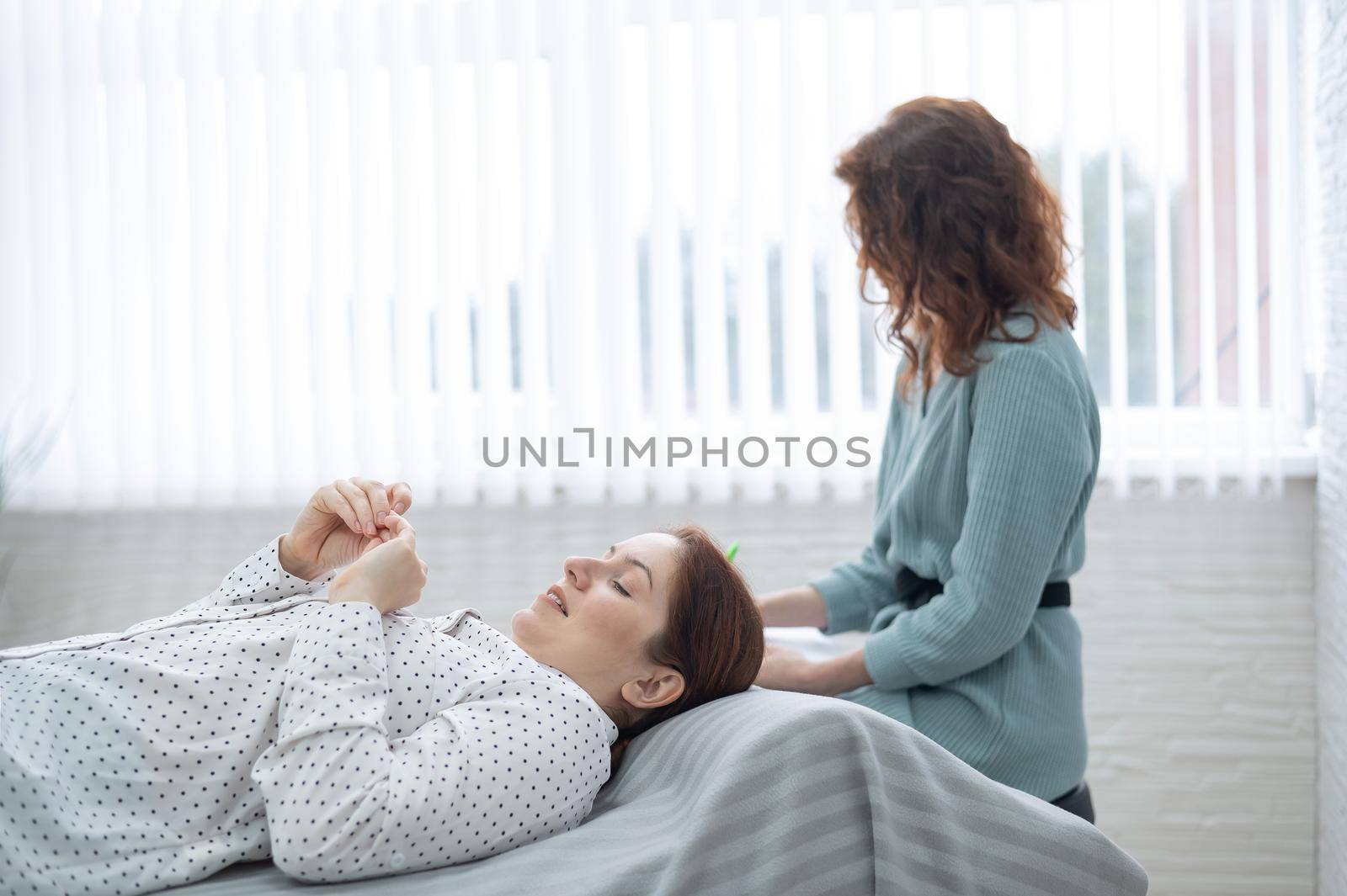 A caucasian woman lies on a couch and expresses her feelings, while a psychologist makes notes on a tablet