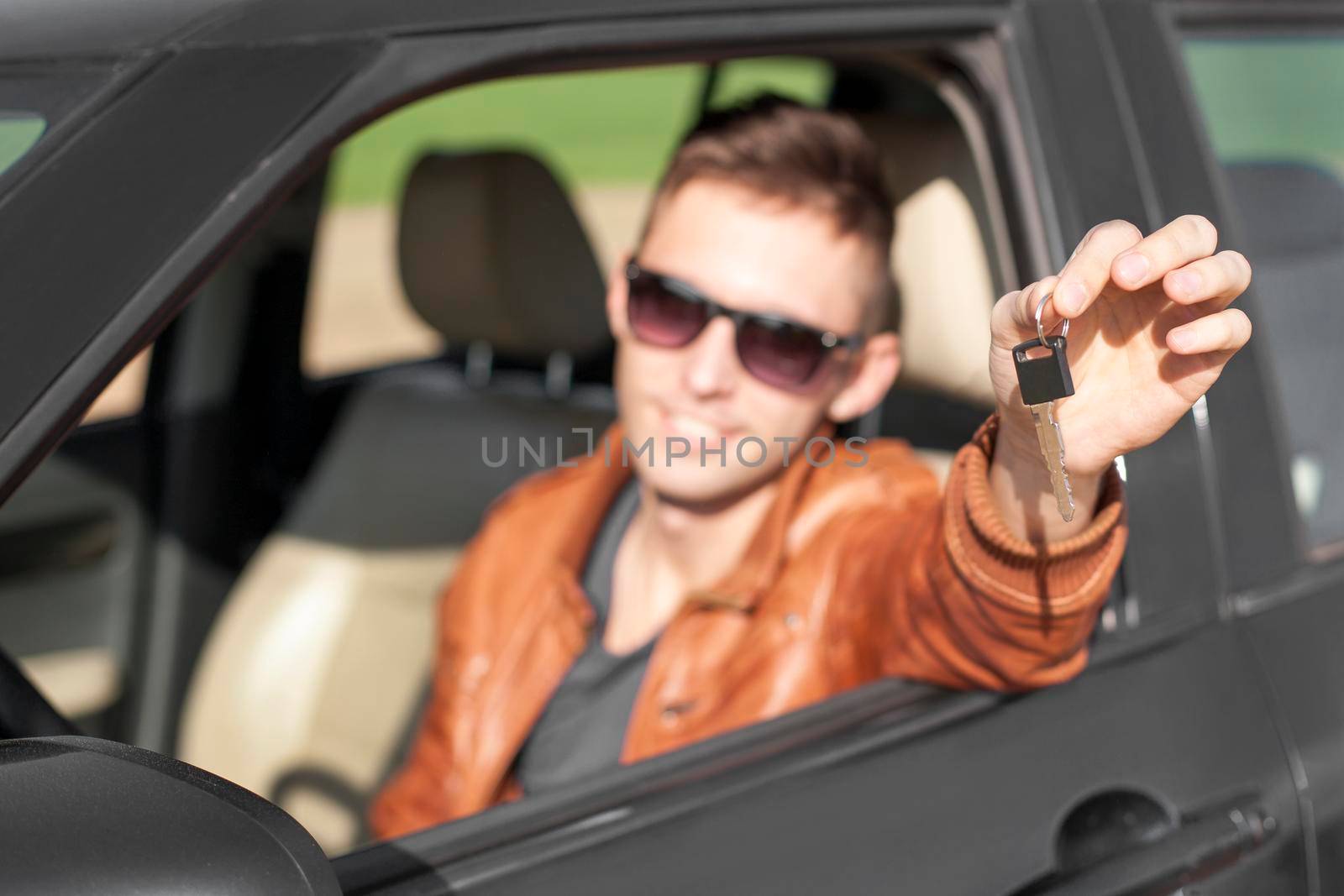 Man sitting inside car and showing keys to new car