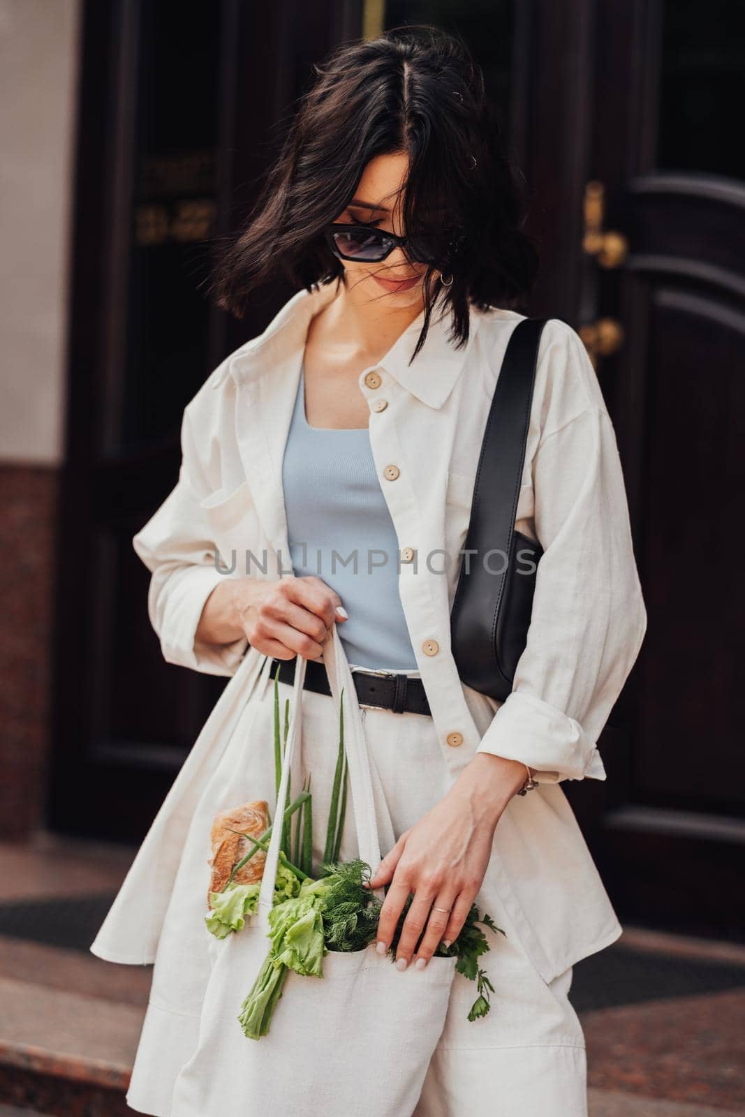 Stylish Young Brunette Woman Holding a Shopping Eco Bag with Groceries Outdoors