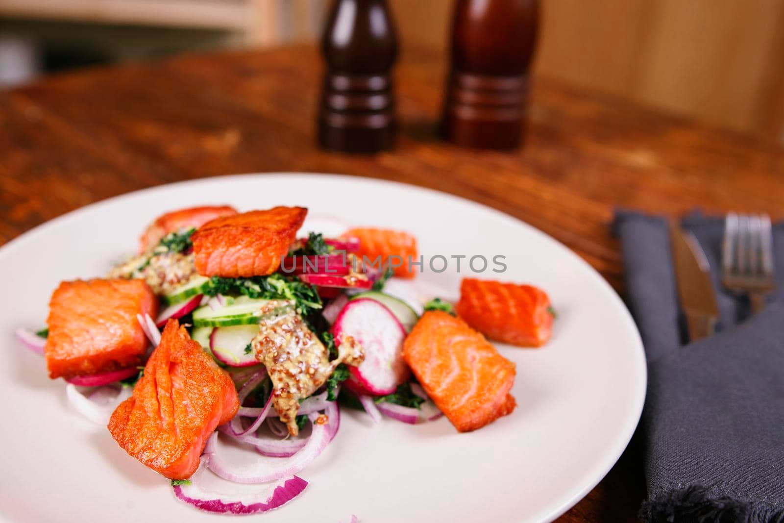 Red fish salmon with radish and spinach, served on white plate on wooden table. rustick style. View from above, top studio shot