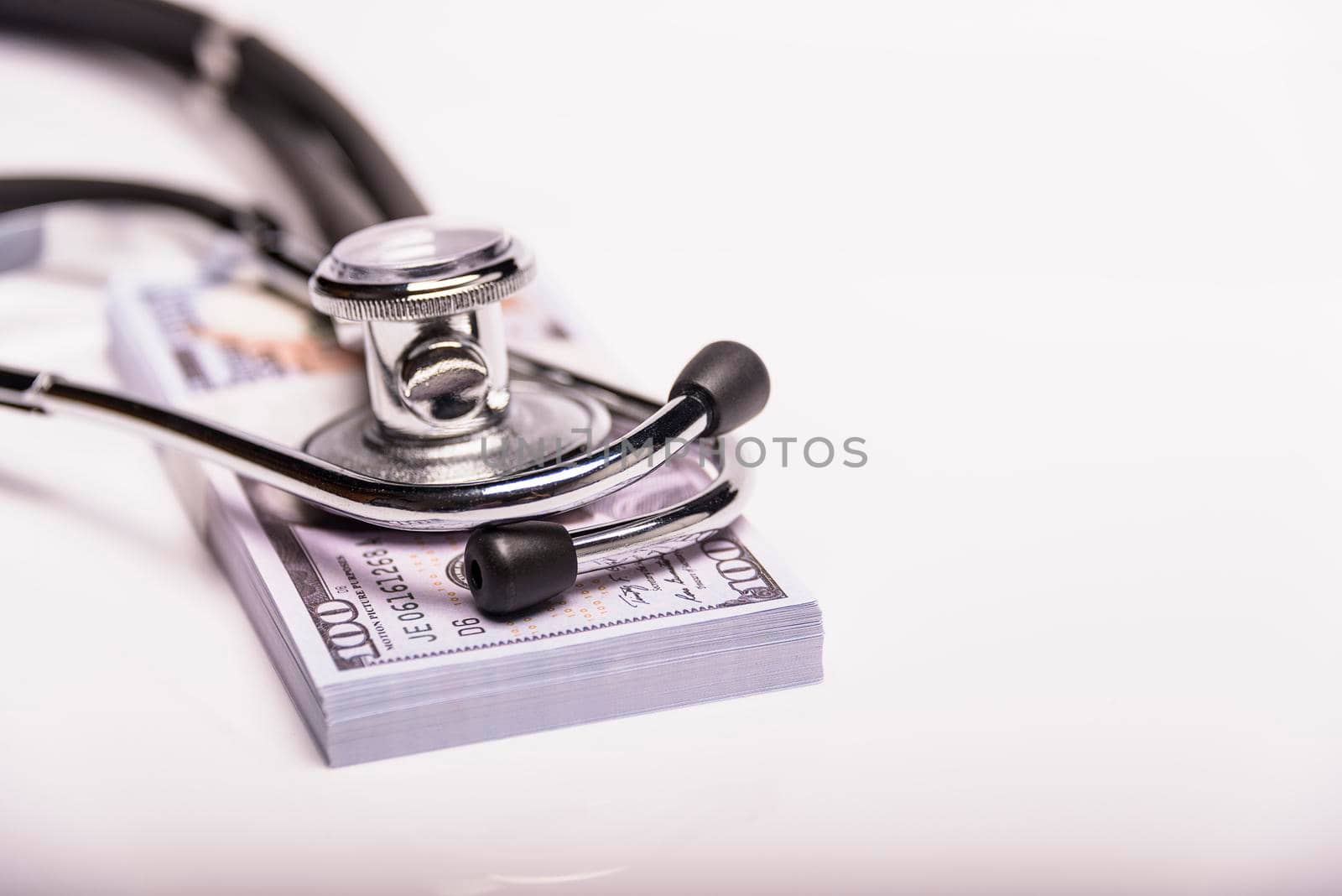 Medical concept - stethoscope over the dollar bills isolated on white background