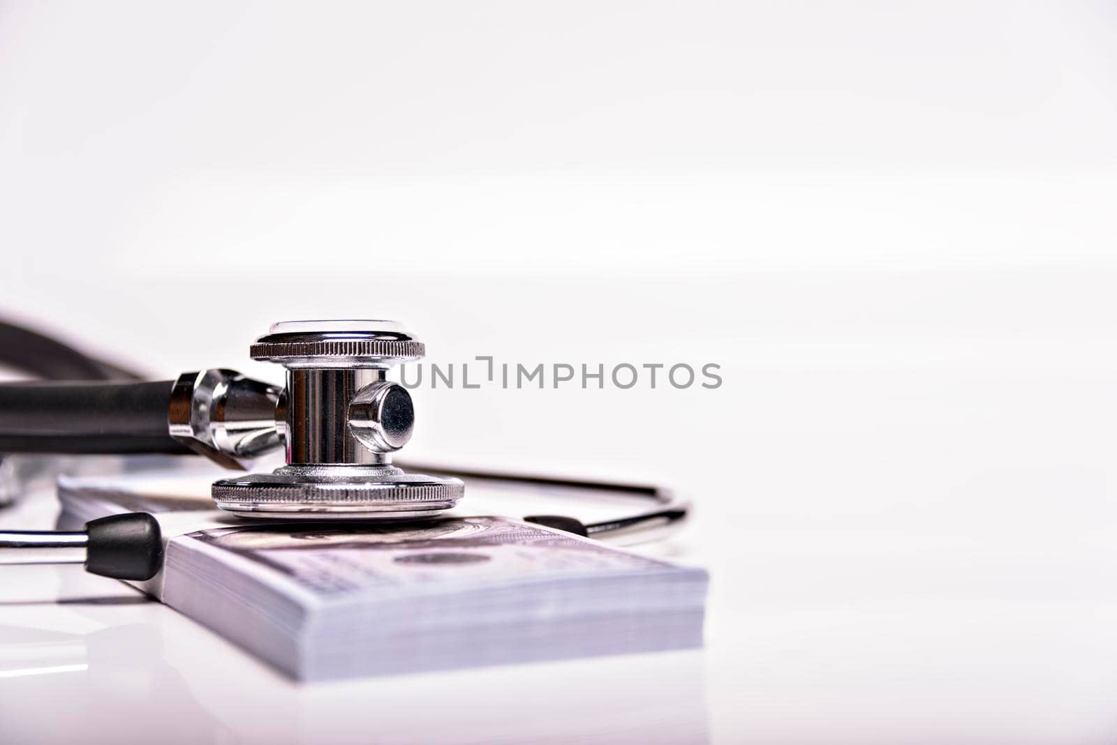 Medical concept - stethoscope over the dollar bills isolated on white background