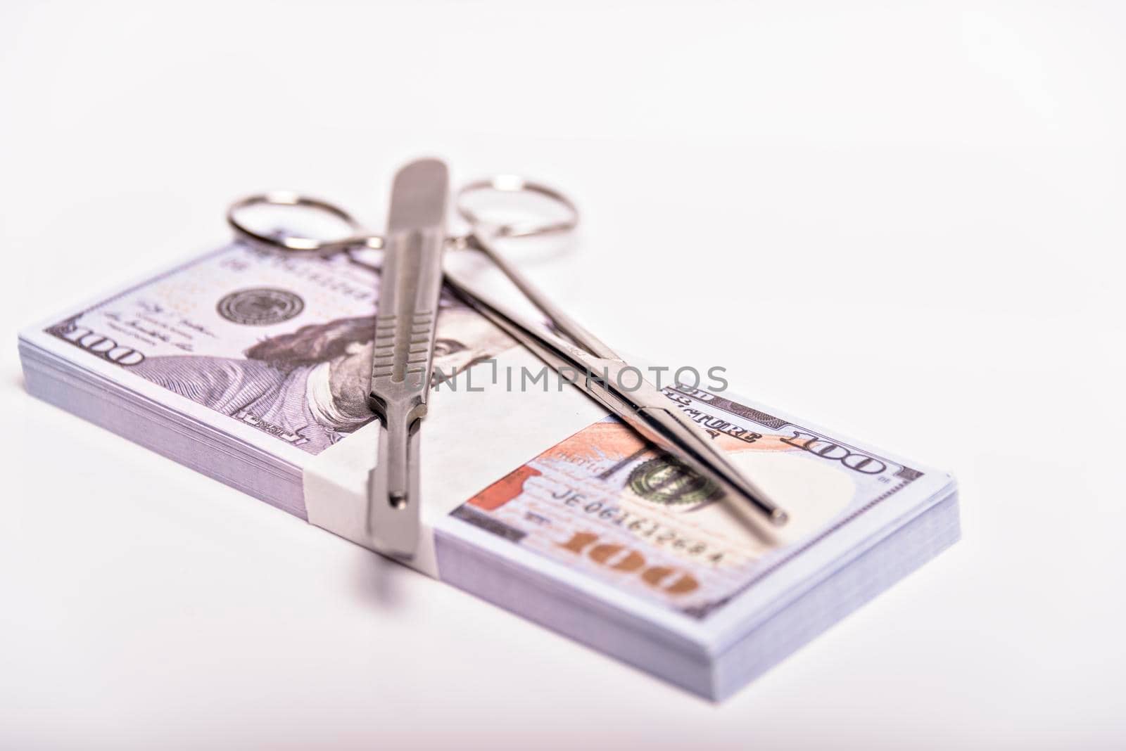 Scalpel and tweezers on pile of cash bills dollars. Concept expensive surgery, medical insurance