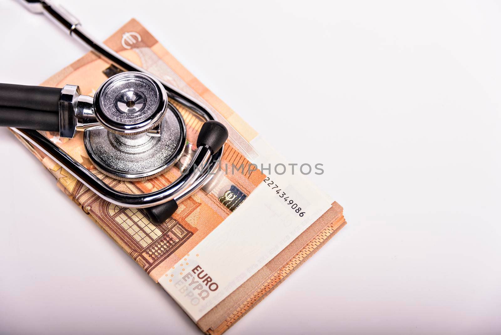 Health care costs conceptual image: stethoscope and pile of money on a medical chart, symbol of health care costs or health insurance, isolated on white background