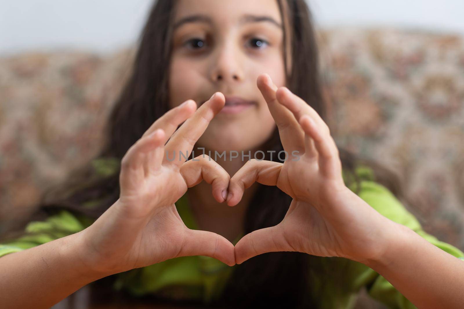 A cute Caucasian child holds a palm in the shape of a heart