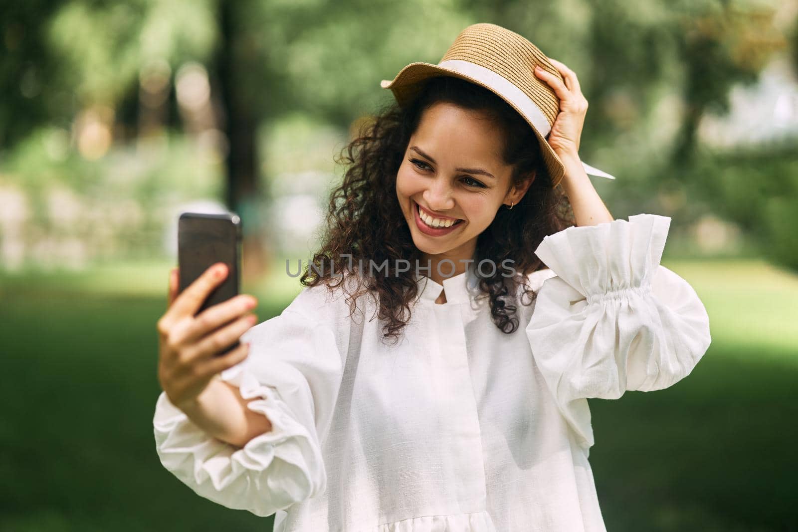 Young beautiful girl in a hat makes a selfie on her phone in the park. High quality photo