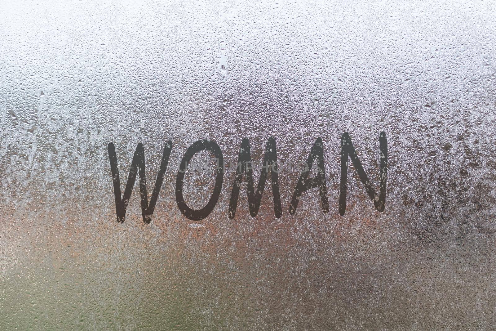 Word woman. Abstract background with drops of water. Inscription on foggy window. Handwritten text on wet glass by Andelov13