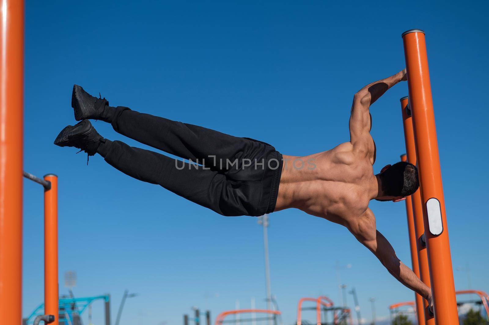 Shirtless man doing human flag outdoors. by mrwed54