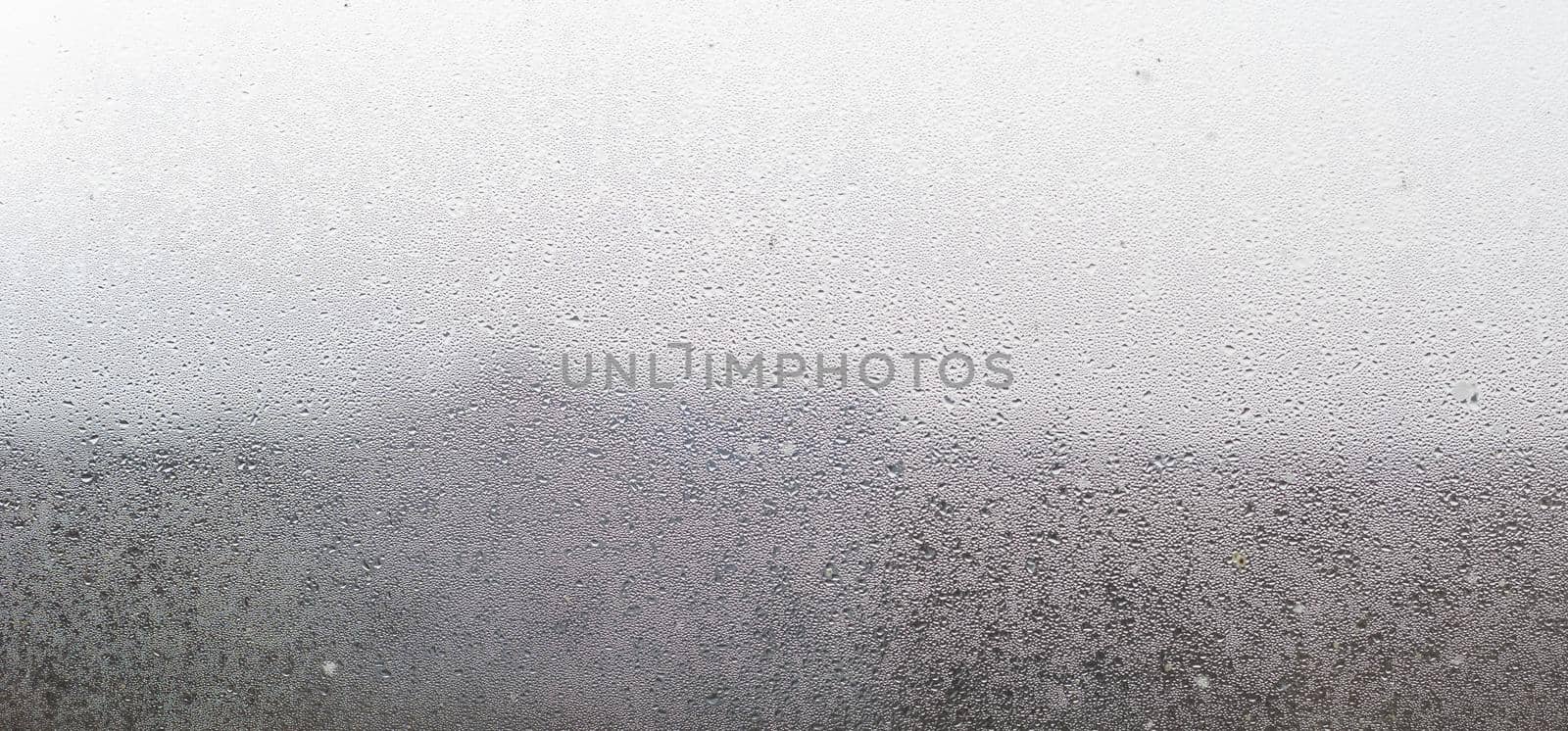 Closeup shot of a steamy window with water drops made in dull day. by Andelov13