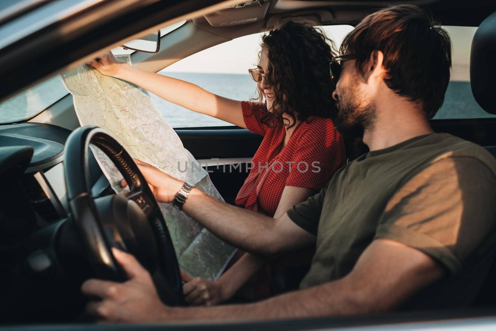 Side View of Man and Woman Sitting in the Car and Checking Map, Young Couple Enjoying Road Trip by Romvy