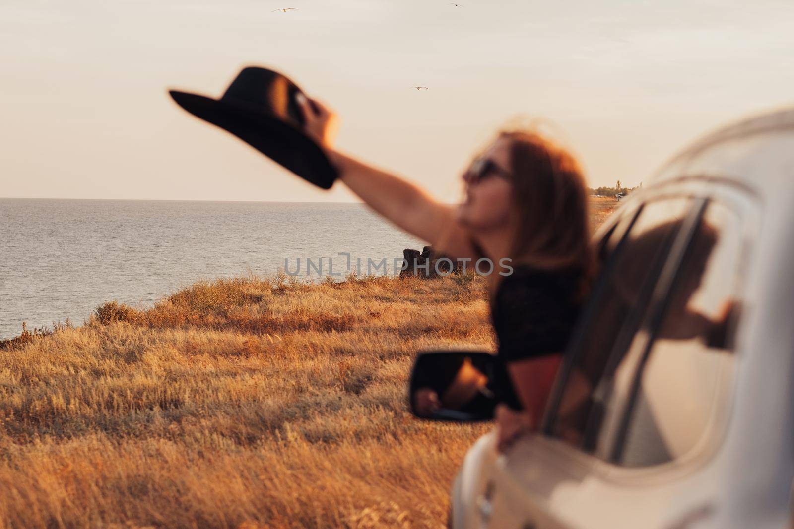 Blurred Young Woman Looks Out of the Car Window on Sea Background, Girl Enjoying Road Trip