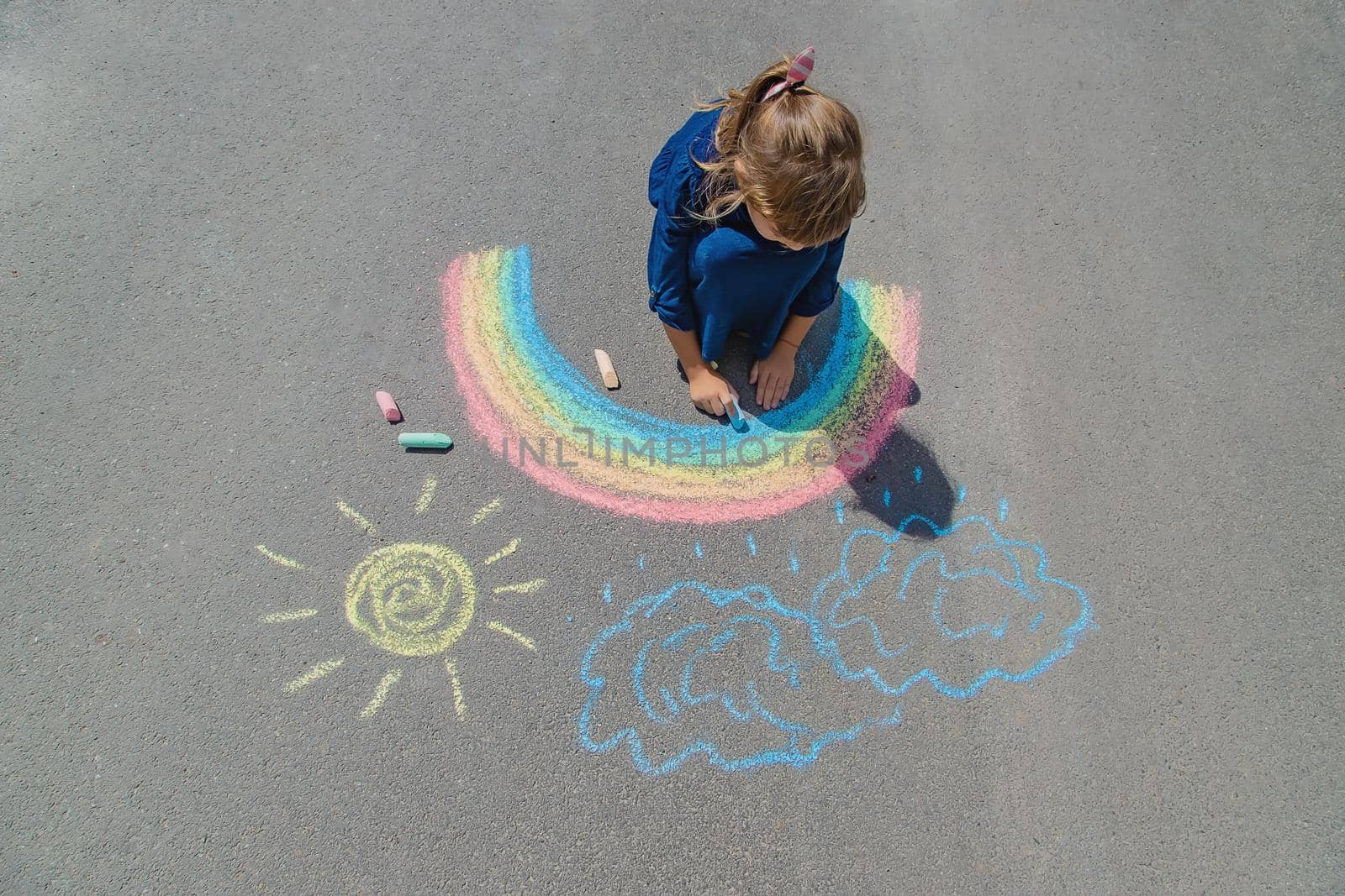 child draws with chalk on the pavement. Selective focus. by yanadjana