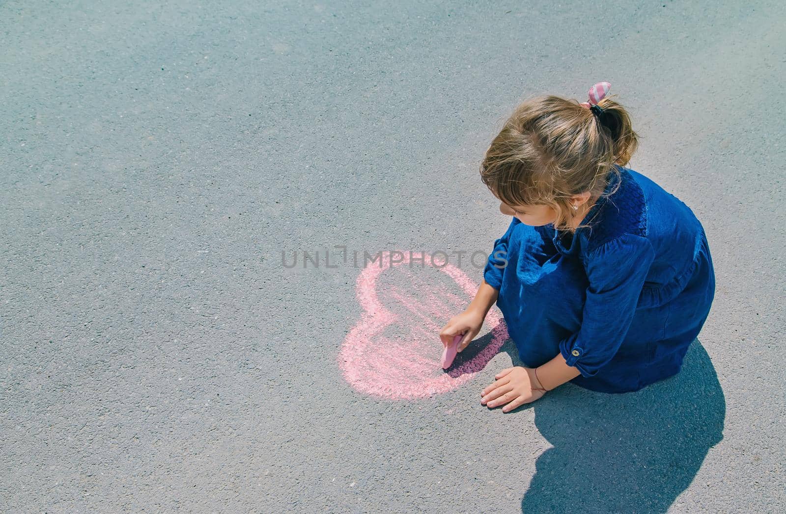 child draws with chalk on the pavement. Selective focus.