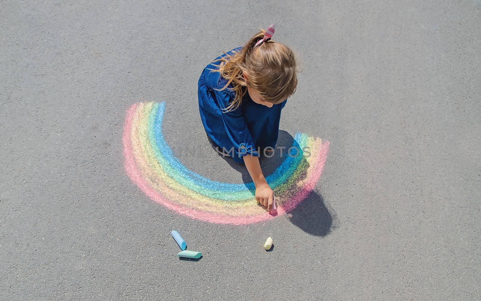 child draws with chalk on the pavement. Selective focus. by yanadjana