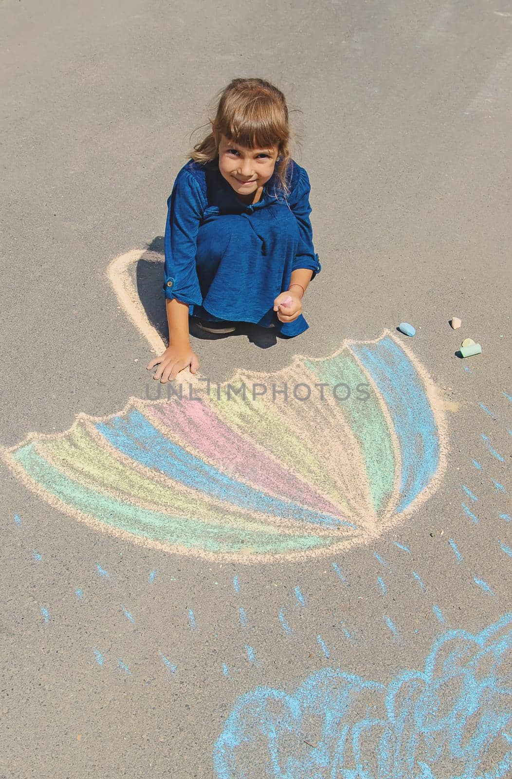 child draws with chalk on the pavement. Selective focus. by yanadjana