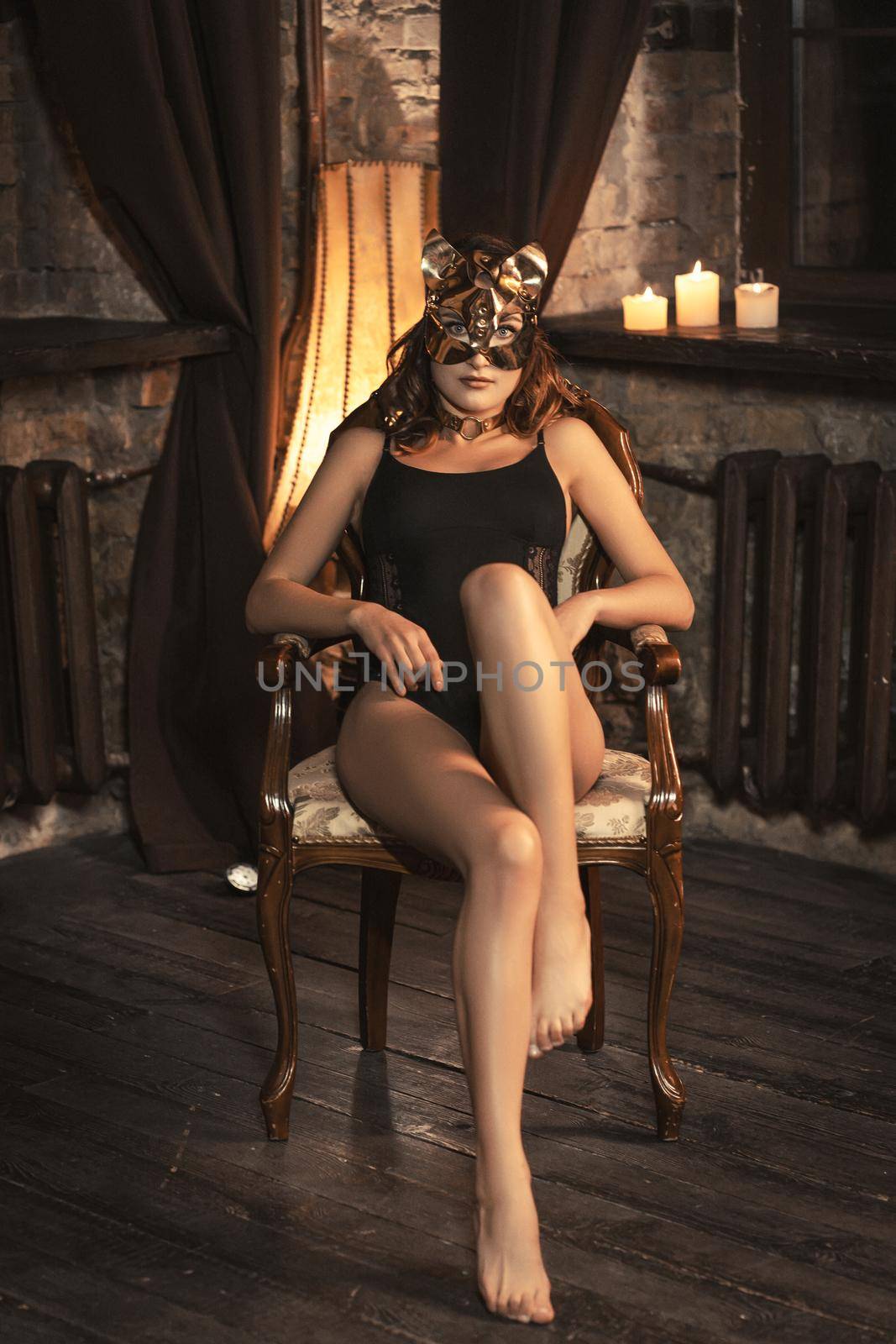 Sexy cat girl in black body lingerie posing laying on the arm chair. Tempting girl in sexy cat mask and underwear. Shot of sexy woman in black lingerie in home interior. Toned image by LipikStockMedia