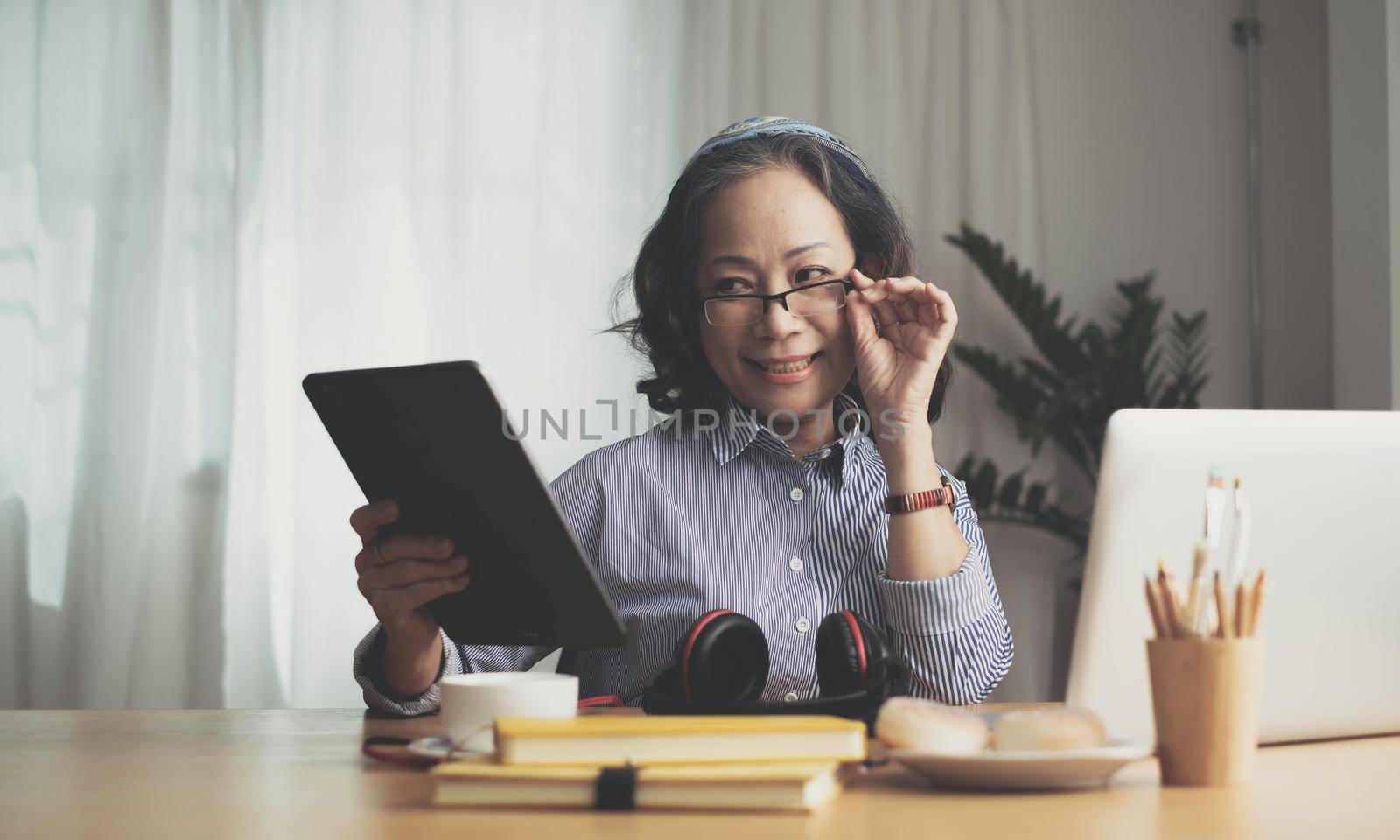 Middle age senior woman sitting at the table at home working using computer laptop with a happy face standing and smiling with a confident smile showing teeth by wichayada