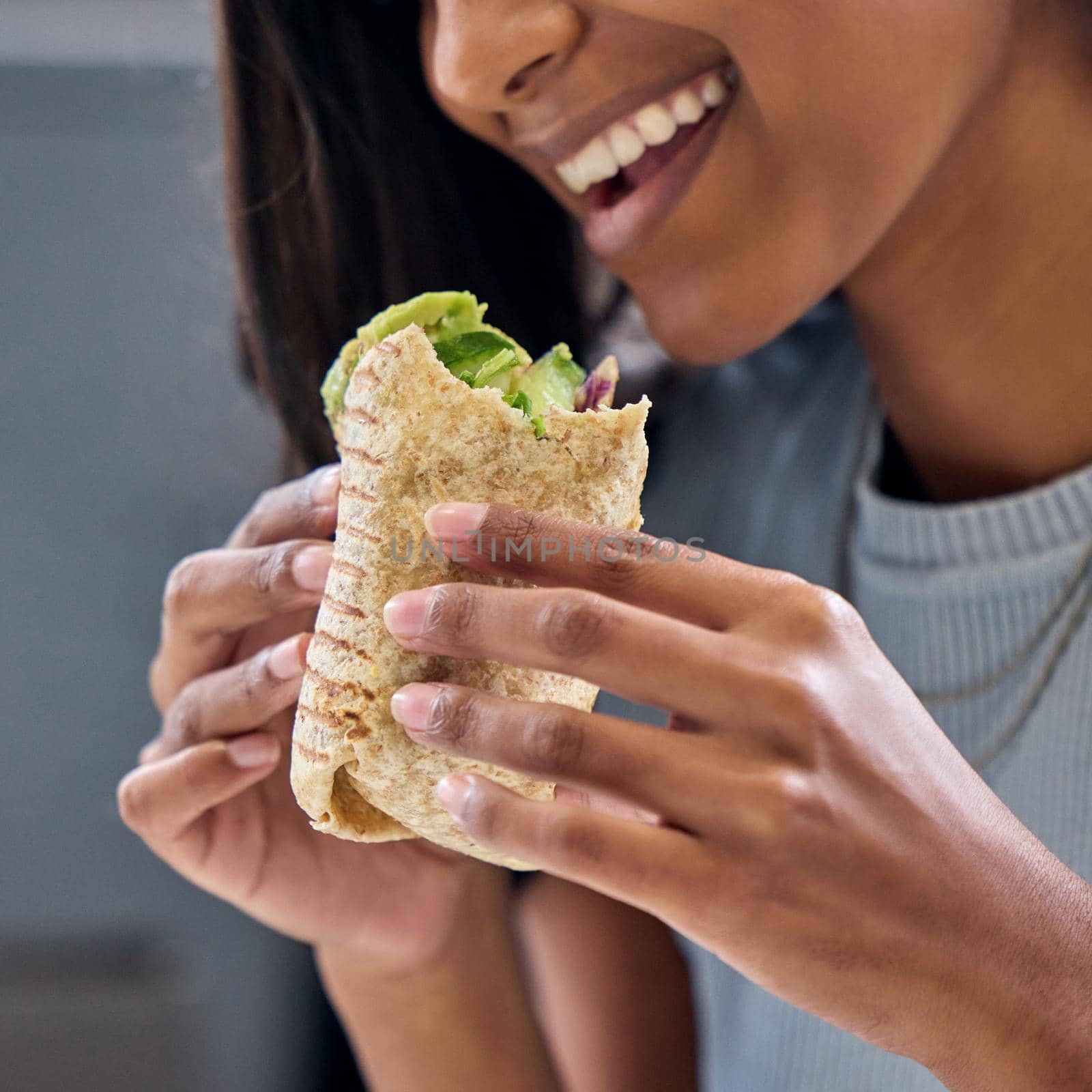 Being healthy has never been so delicious. Shot of a woman enjoying a wrap. by YuriArcurs