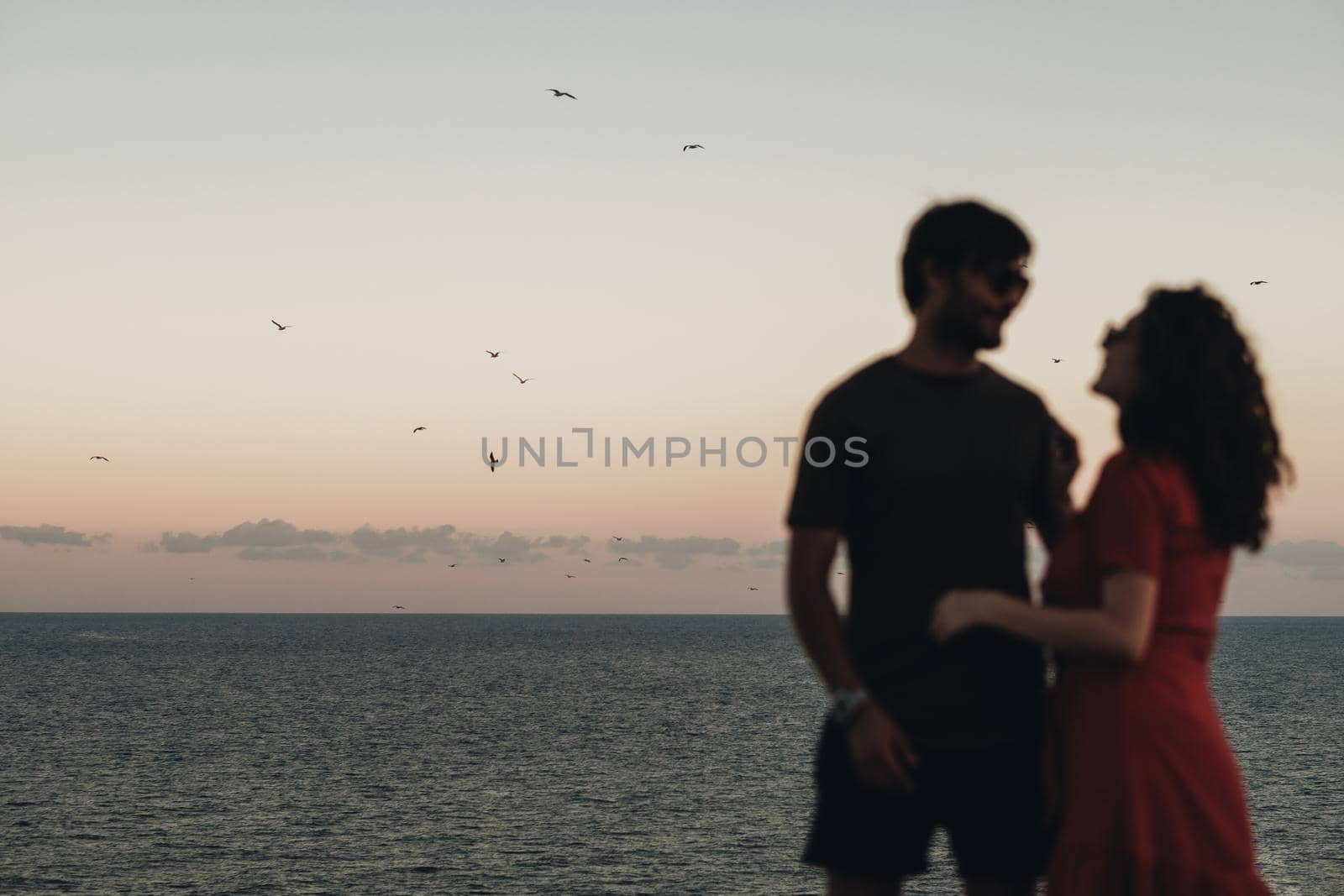 Unfocused Blurred Couple Standing on Background of Sea After Sunset at Evening, Seagulls Flying Over Water