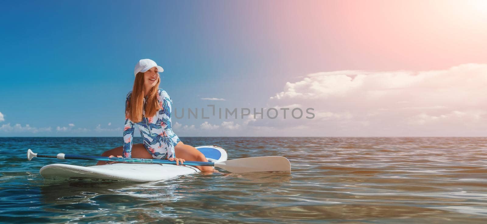 Healthy happy fit woman in bikini relaxing on a sup surfboard, floating on the clear turquoise sea water. Recreational Sports. Stand Up Paddle boarding. Summer fun, holidays travel. Active lifestyle by panophotograph