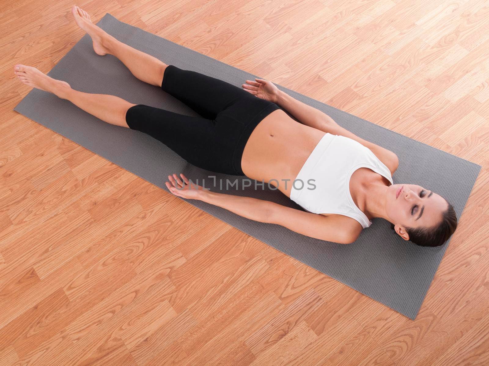 Feeling at peace by living in the present. Shot of a beautiful young woman lying on an exercise mat. by YuriArcurs