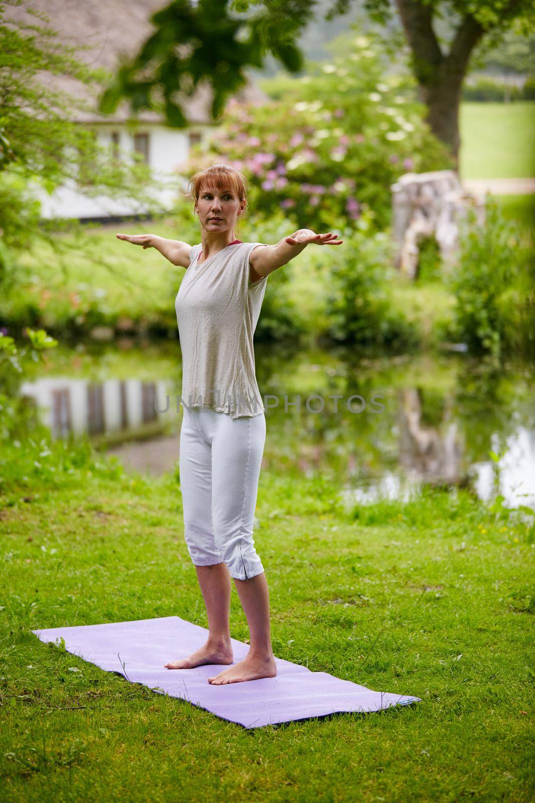 Meditating in nature. Shot of a woman doing yoga in the park. by YuriArcurs